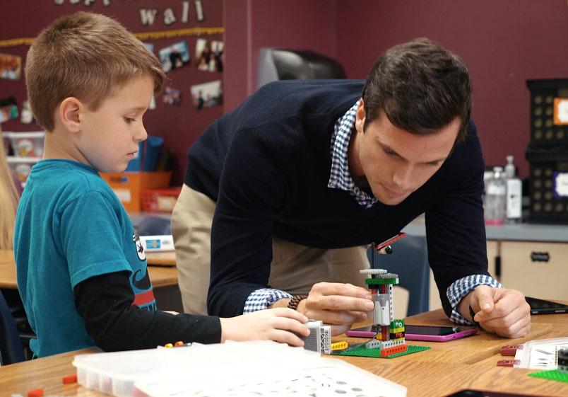 A Bricks 4 Kidz owner helping a student with his build